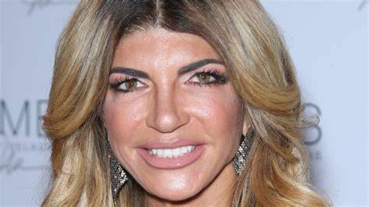 Teresa Giudice sitting on a beach bed in an orange halter bikini